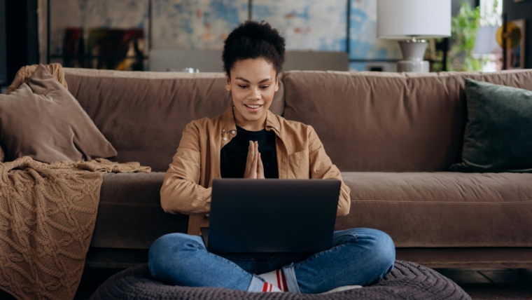 Women with laptop on her knee and sat on the floor.