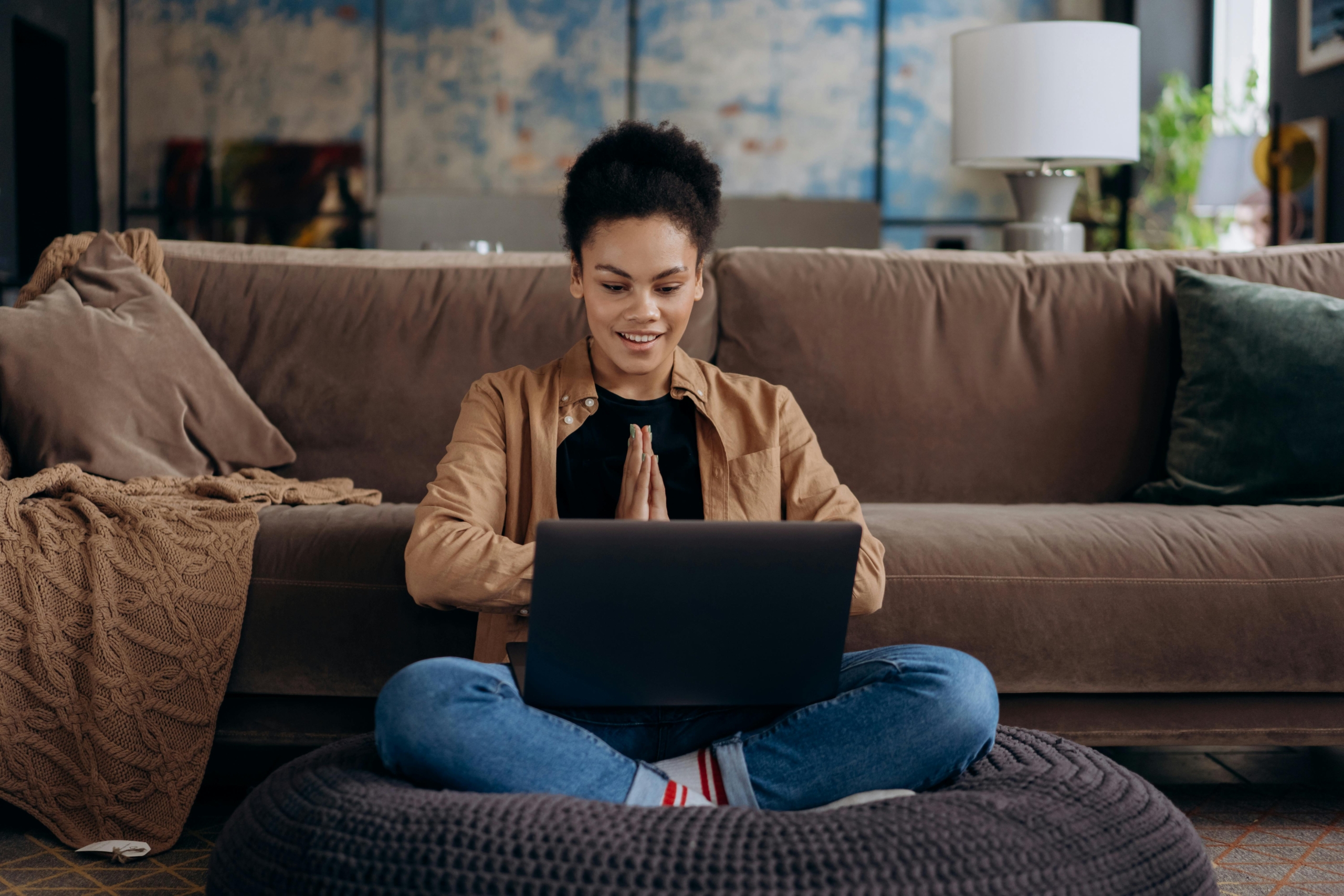 Women with laptop on her knee and sat on the floor.